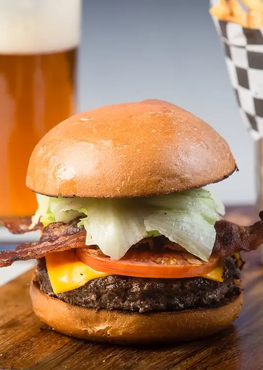 cali vibe burger sits on a plate beside fries and a beer
