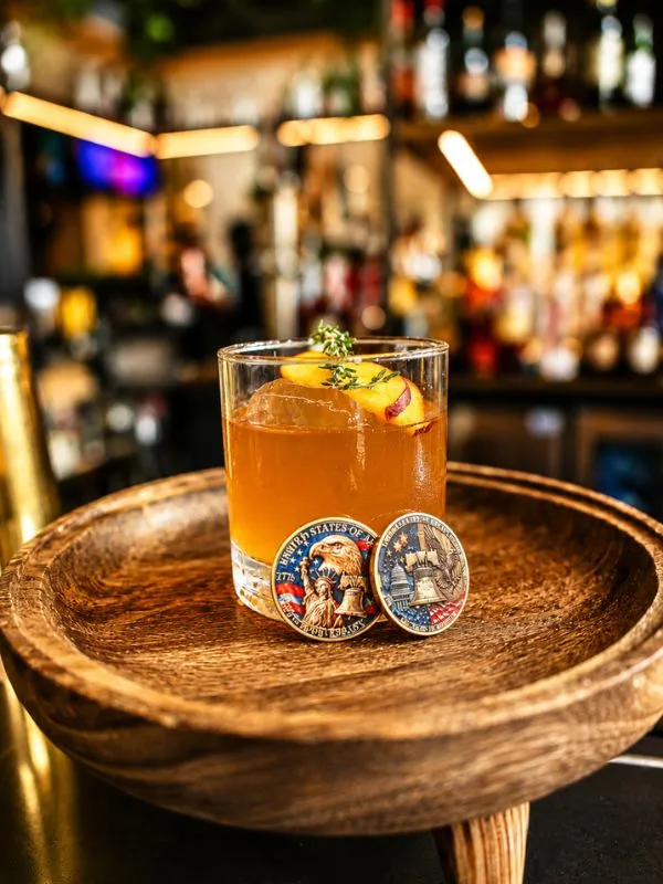 A cocktail made with bourbon and garnished with grilled peaches